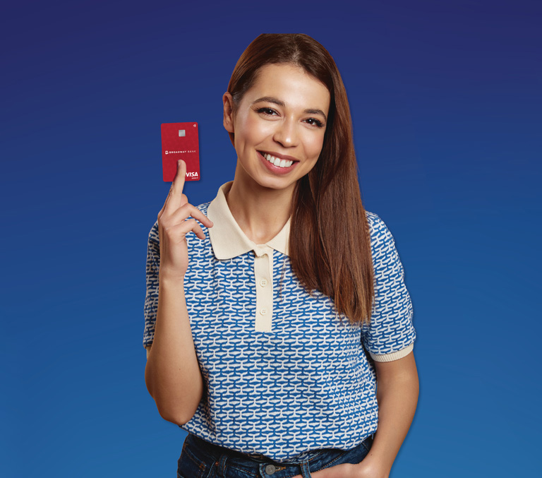 A lady smilling holding a Broadway Bank debit card on a blue background