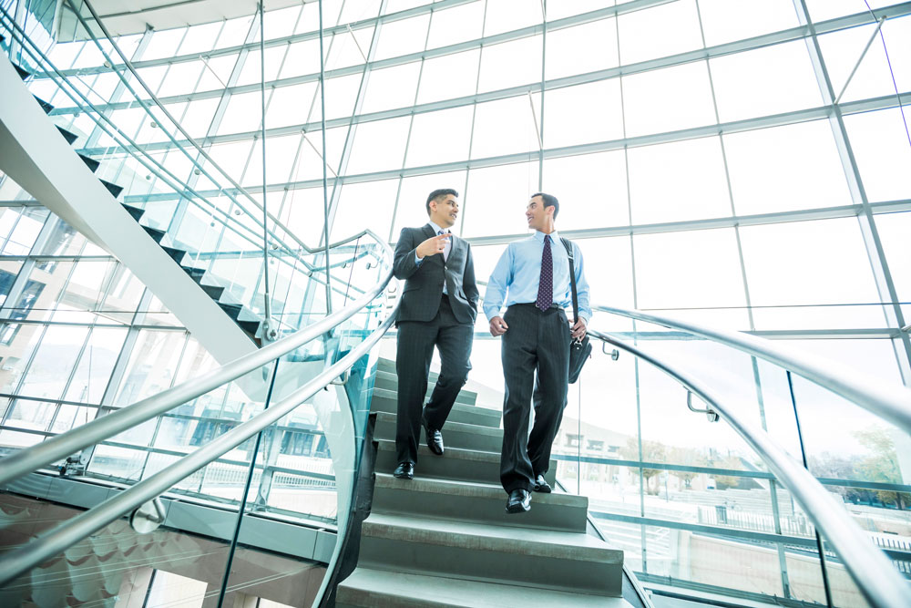 Businessmen descending staircase and talking 