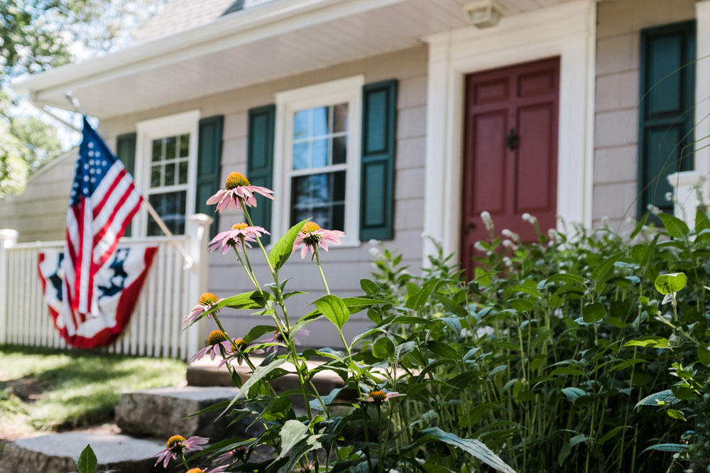 Exterior image of home with US flag hanging on the front porch