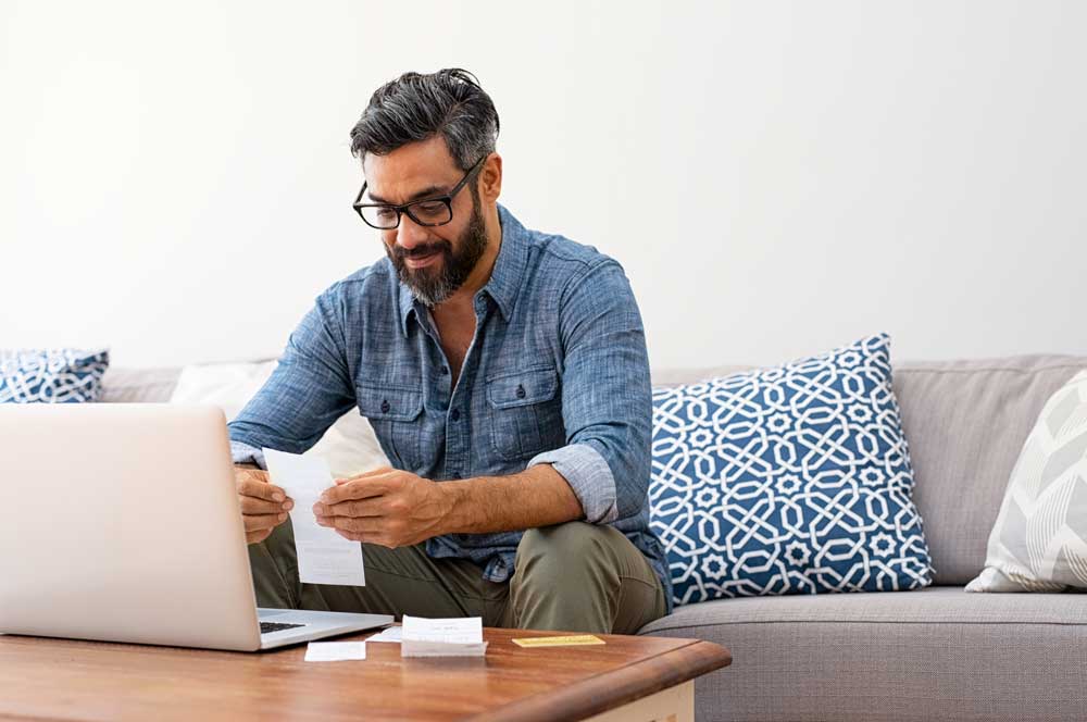 Man sitting in living room at computer paying bills