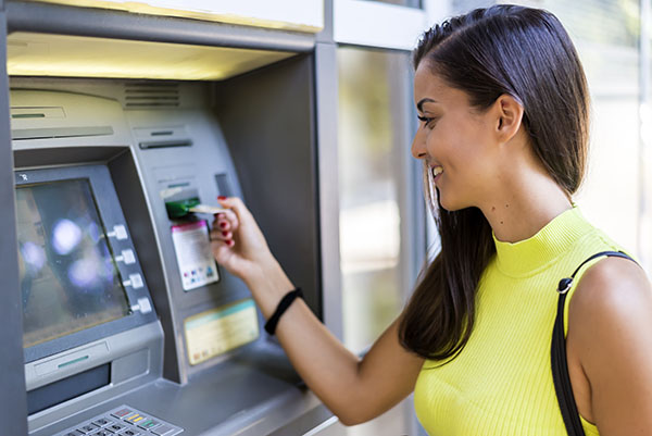 A woman in a yellow shirt using an Allpoint ATM