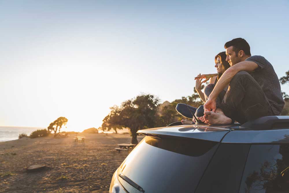 A couple sits on top of their new car purchased with a Broadway Bank auto loan