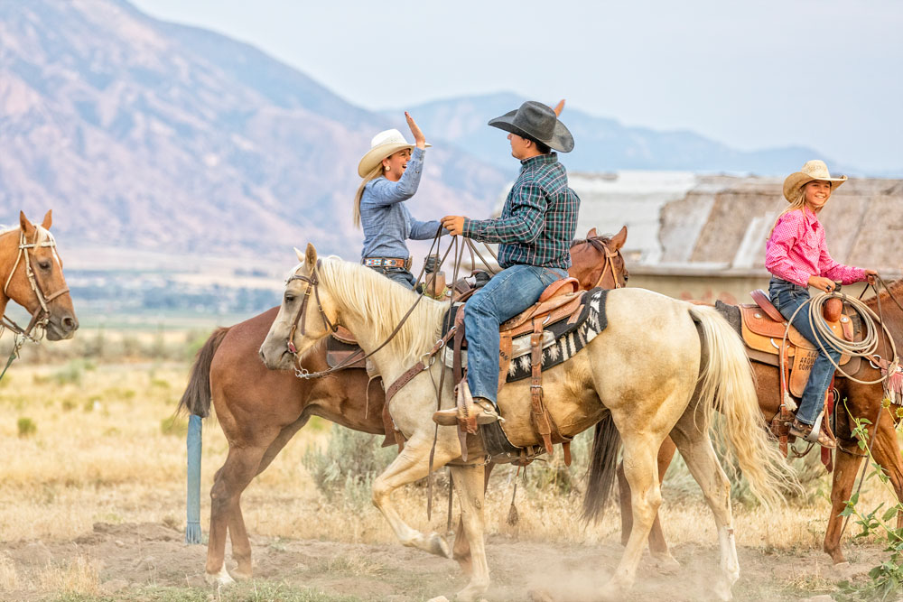 a family rides horses on their ranch together