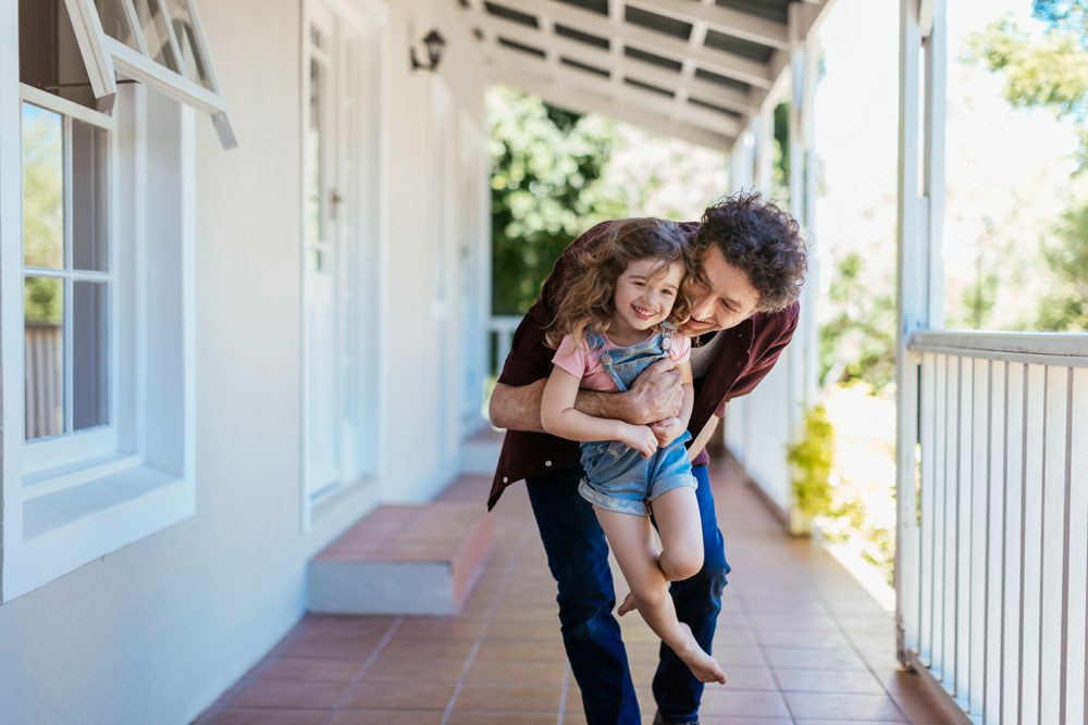 Father and child on front porch of home purchased using a low down payment loan
