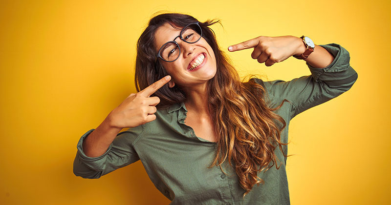 A woman with brown hair and glasses smiling after receiving a free checking account from Broadway Bank