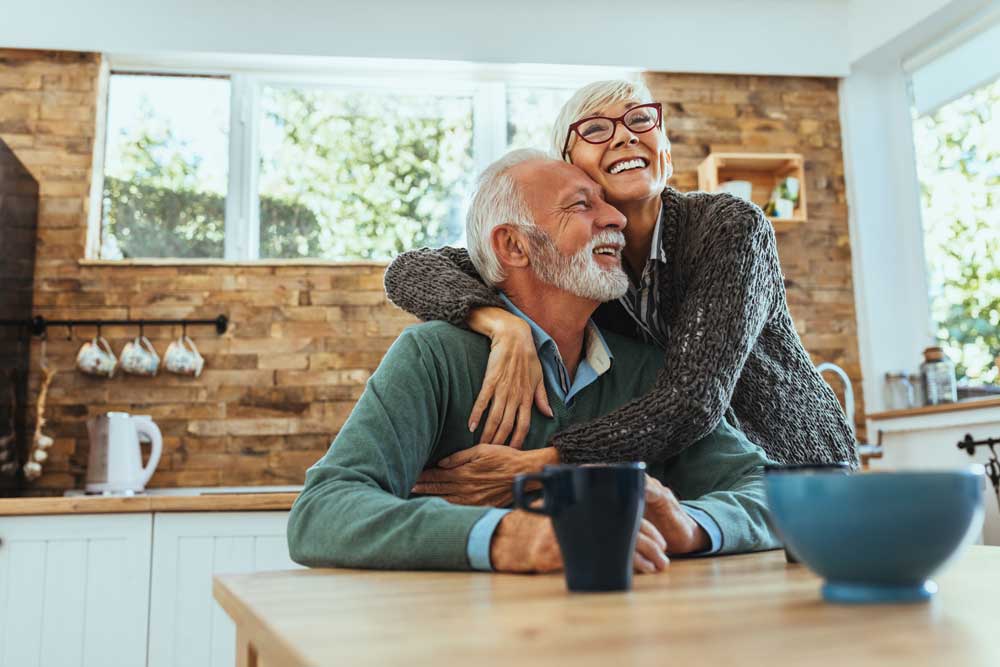 an older couple smiles while hugging each other