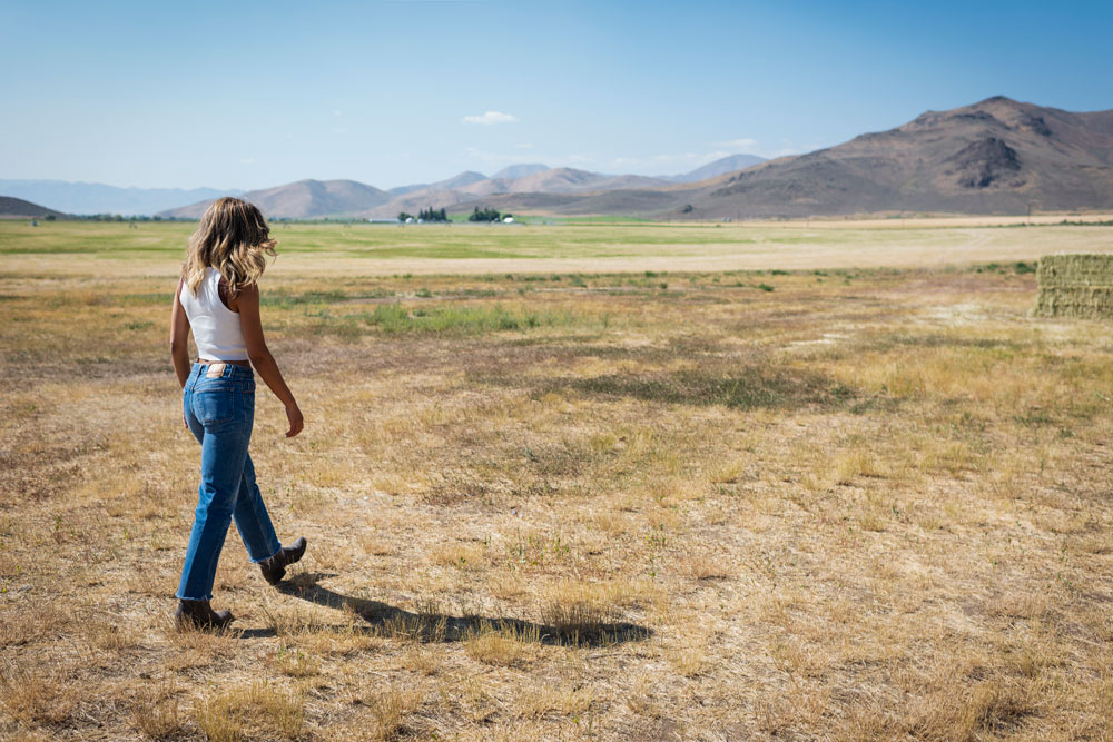 a woman walks through an open field