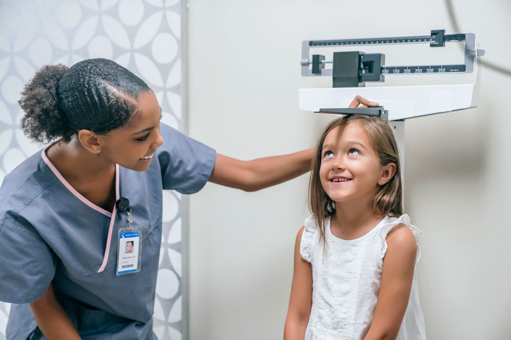 a nurse takes a young girls height in the hospital
