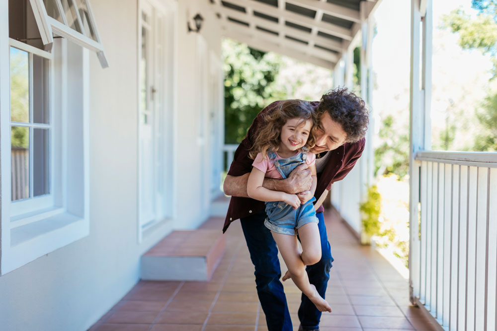 Father with daughter on the front porch of their new home