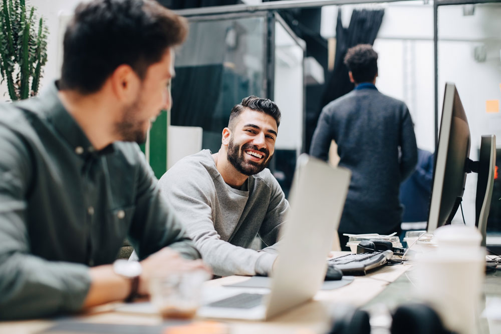 Hispanic male coworkers talking to each other in office setting