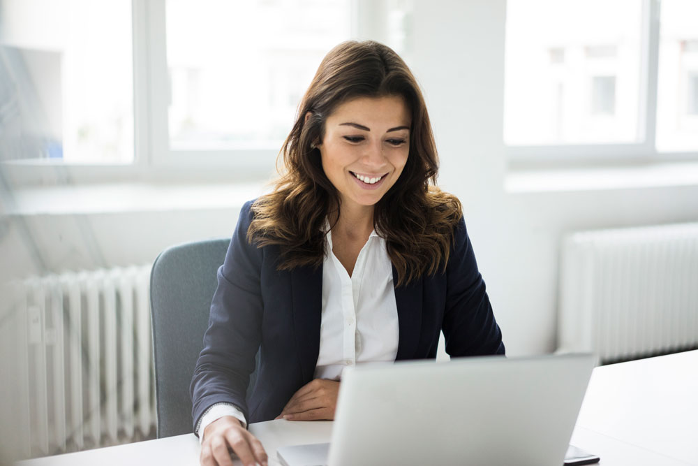 Hispanic woman smiling, browsing the internet on a computer