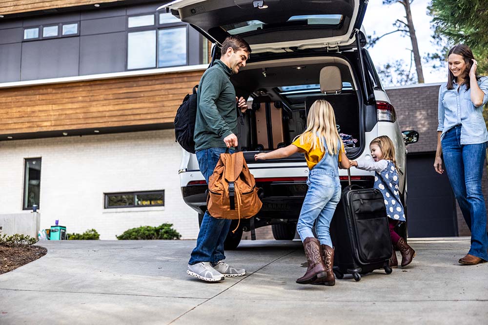 A family loading their car with luggage preparing for a road trip