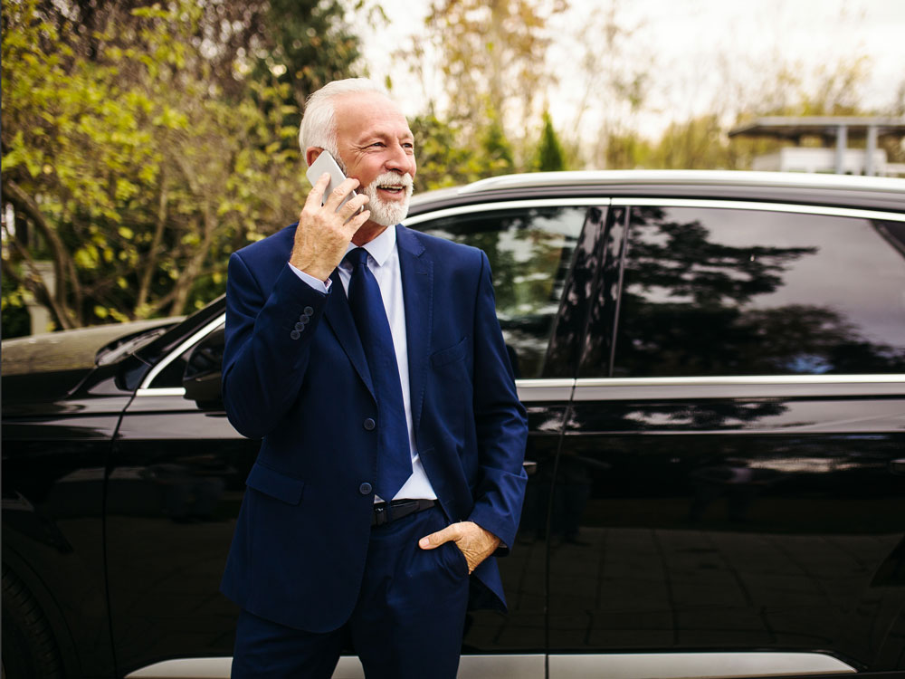 a man stands in front of his luxury automobile