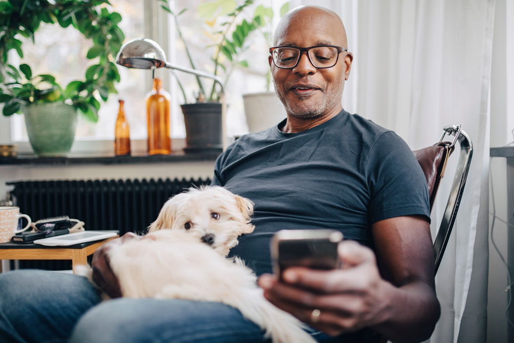 man sitting with his dog looking at his phone