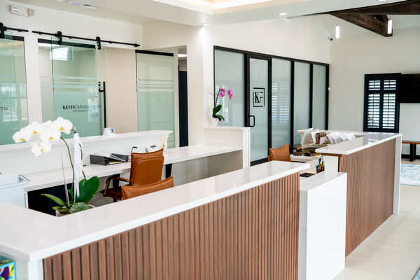 Modern reception area featuring stylish wood and white countertops, with two seating areas and decorative plants.