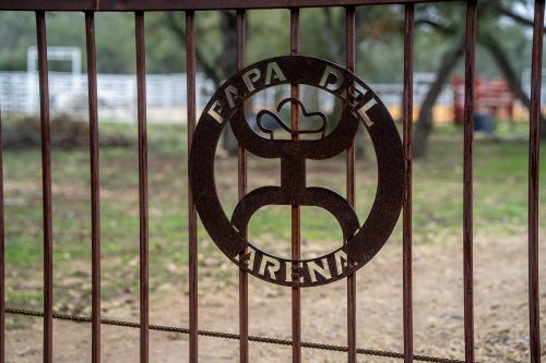 Metal gate with the logo of "Papa del Arena" featured prominently in a rustic setting.
