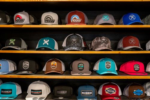 A display of various caps showcasing different logos and designs, arranged neatly on shelves.