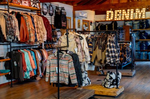 A clothing store interior showcasing a variety of denim and casual apparel on racks, with a "DENIM" sign in the background.