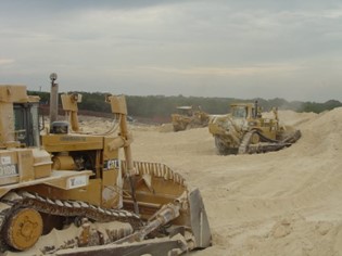 Heavy machinery operating on a construction site, moving sand and earth.