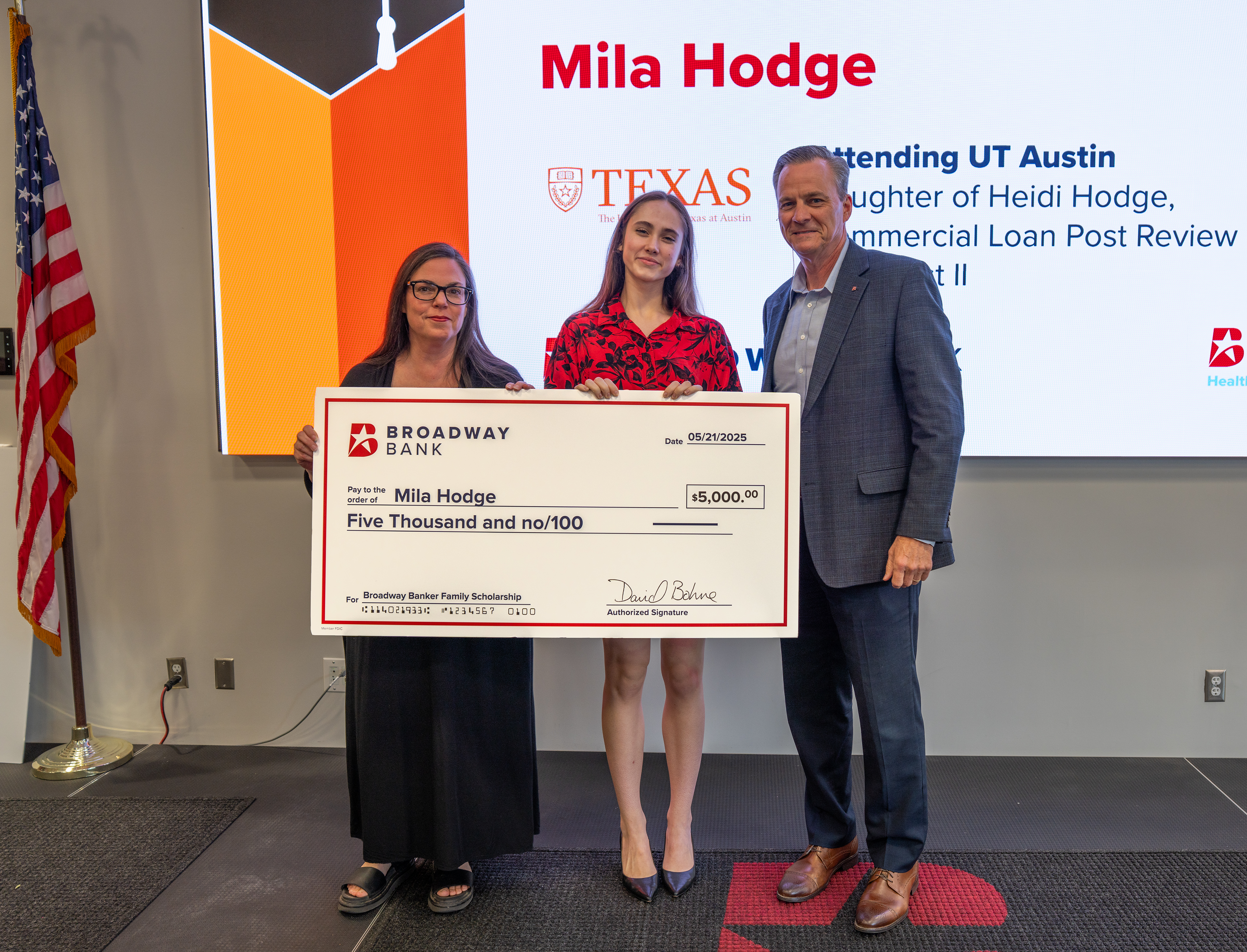 A scholarship award presentation featuring Mila Hodge holding a large check for $5,000, flanked by her mother and a representative from Broadway Bank.