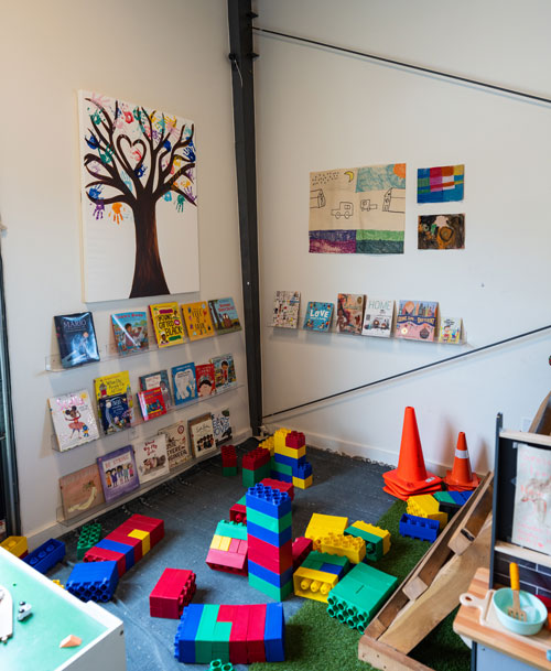 An imaginative play area featuring colorful building blocks, children's books on a shelf, and vibrant artwork on the walls.