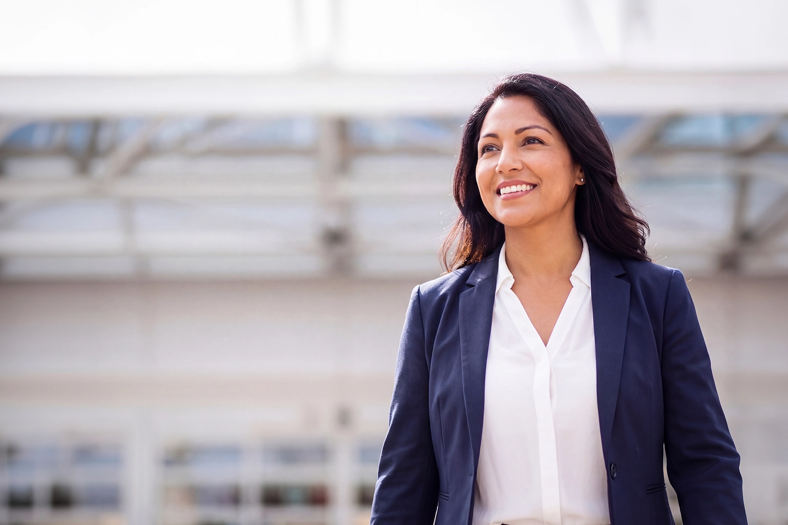 A young lady wearing a blue suit walking and smiling